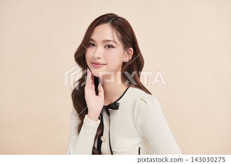 A beautiful young Asian woman with clean, fresh skin against a beige background. Skincare, facial treatment, cosmetology, beauty, and spa. An elegant portrait of an Asian woman. A beautiful young Asian woman with clean, fresh skin against a beige background. Skincare, facial treatment, cosmetology, beauty, and spa. An elegant portrait of an Asian woman. 143030275