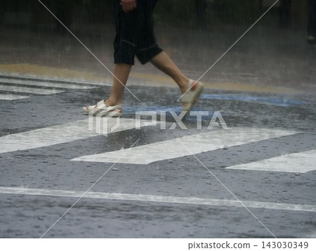 Pedestrians crossing a crosswalk on a rainy day Pedestrians crossing a crosswalk on a rainy day 143030349