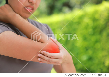 Close up unhappy Asian woman touching her elbow with a red highlighted area indicating severe joint pain, arthritis, muscle ache or sports injury. Healthcare, physical therapy, and medical concept. Close up unhappy Asian woman touching her elbow with a red highlighted area indicating severe joint pain, arthritis, muscle ache or sports injury. Healthcare, physical therapy, and medical concept. 143030481