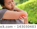 Stressed young Asian woman holding her elbow with red highlighted area indicating severe joint pain, arthritis, muscle sprain or sports injury. Healthcare, physical therapy, and medical care concept. 143030483