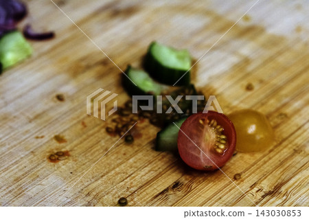 Left over salad from dinner chopped cucumber tomato onion food waste on chopping board 143030853
