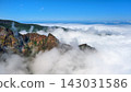 Mountain peaks covered by low clouds under a bright blue sky with rugged cliffs and green vegetation in a scenic natural landscape, Madeira, Portugal. 143031586