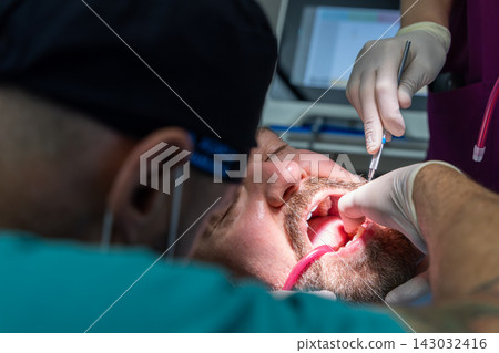 Dentist seating implant restoration during patient treatment in dental clinic Dentist seating implant restoration during patient treatment in dental clinic 143032416