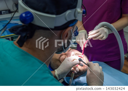 Dental Team Performs Implant Restoration Treatment With Suction in Clinic Dental Team Performs Implant Restoration Treatment With Suction in Clinic 143032424