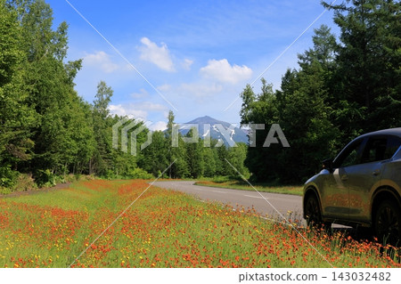 A single road leading to the smoke-emitting Tokachi-dake mountain, and a breathtaking view against a clear blue sky. A single road leading to the smoke-emitting Tokachi-dake mountain, and a breathtaking view against a clear blue sky. 143032482
