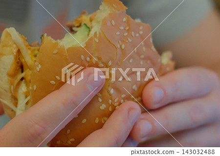Close up of hands holding a fresh cheeseburger with a bite taken out Close up of hands holding a fresh cheeseburger with a bite taken out 143032488