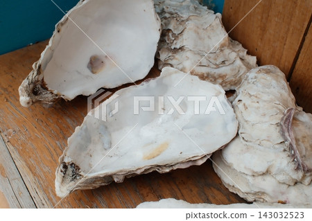 Empty oyster shells resting on a wooden surface during the daytime Empty oyster shells resting on a wooden surface during the daytime 143032523