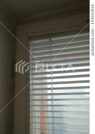 White window blinds covering a glass pane in a room during the daytime White window blinds covering a glass pane in a room during the daytime 143032658