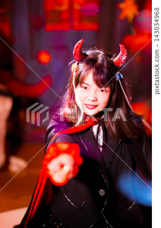 一幅充滿萬聖節氛圍的電影風格肖像畫,畫中一個女孩裝扮成惡魔,手持一根發光的魔法棒。 一幅充滿萬聖節氛圍的電影風格肖像畫,畫中一個女孩裝扮成惡魔,手持一根發光的魔法棒。 143034968
