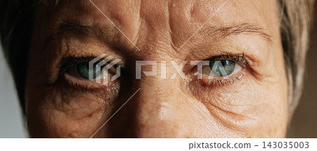 Elderly female with blue eyes close-up revealing facial details and wrinkles Elderly female with blue eyes close-up revealing facial details and wrinkles 143035003