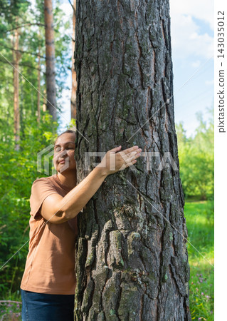 Mature caucasian female embracing tree in lush forest setting. Mental health, female harmony Mature caucasian female embracing tree in lush forest setting. Mental health, female harmony 143035012