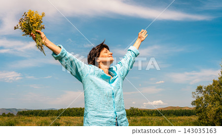 Woman standing in green field with her arms outstretched, facing sun, embracing happiness and beauty of nature. Women's mental health, accepting one's age Woman standing in green field with her arms outstretched, facing sun, embracing happiness and beauty of nature. Women's mental health, accepting one's age 143035163