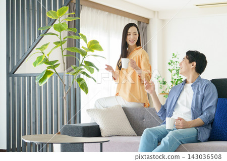 一對年輕的日本明星夫婦在客廳裡喝飲料 一對年輕的日本明星夫婦在客廳裡喝飲料 143036508