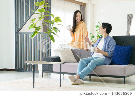 一對年輕的日本明星夫婦在客廳裡喝飲料 一對年輕的日本明星夫婦在客廳裡喝飲料 143036509