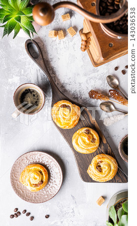 Freshly baked pastries on a wooden board with coffee and decorative elements in a cozy setting Freshly baked pastries on a wooden board with coffee and decorative elements in a cozy setting 143036538