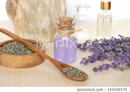 Dry lavender flowers in wooden bowl and bottle of essential lavender oil or infused water on white background. Natural organic ingredients for herbal cosmetics. Spa massage set, lavender product Dry lavender flowers in wooden bowl and bottle of essential lavender oil or infused water on white background. Natural organic ingredients for herbal cosmetics. Spa massage set, lavender product 143036578
