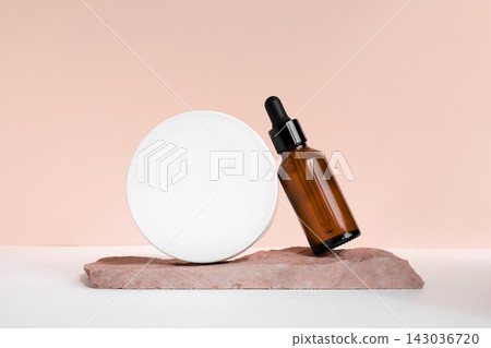 Amber glass dropper cosmetic bottle, white podium. Natural skin care SPA beauty product design. Mineral organic oil on beige background. Mock-Up. Oily pipette. Face and body treatment. Front view Amber glass dropper cosmetic bottle, white podium. Natural skin care SPA beauty product design. Mineral organic oil on beige background. Mock-Up. Oily pipette. Face and body treatment. Front view 143036720