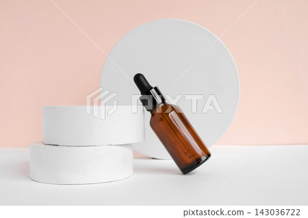 Amber glass dropper cosmetic bottle, white podium. Natural skin care SPA beauty product design. Mineral organic oil on beige background. Mock-Up. Oily pipette. Face and body treatment. Front view Amber glass dropper cosmetic bottle, white podium. Natural skin care SPA beauty product design. Mineral organic oil on beige background. Mock-Up. Oily pipette. Face and body treatment. Front view 143036722
