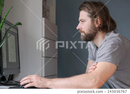 Man working on desktop computer at home. Handsome businessman or freelancer in casual clothes working remotely from home. Pensive young Caucasian man sit at table, work online, pondering thinking Man working on desktop computer at home. Handsome businessman or freelancer in casual clothes working remotely from home. Pensive young Caucasian man sit at table, work online, pondering thinking 143036767