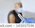 Syringe Close Up and Blurred Senior Man In Clinic on Background. Older People Vaccination. Monkeypox or COVID Vaccine Injection to Mature Man. Protection of Elderly Patient. Old Man in Hospital 143037596