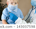 Medical examining boy in clinic. Little child checked by doctor. Pediatrician with stethoscope with face mask and toddler in a hospital. Check heart lungs of kid. Pediatric checkup in hospital 143037598