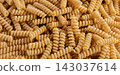 Gluten Free Cornmeal Pasta Wallpaper. Spiral Raw Macaroni from Corn and Rice flour rotating on Turntable. Close Up Top View. Uncooked Pasta Spinning. Full Frame. Food Background. Fusilli Bucati Corti 143037614