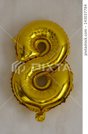 Shiny metallic gold number eight balloon isolated on a light neutral background Shiny metallic gold number eight balloon isolated on a light neutral background 143037784
