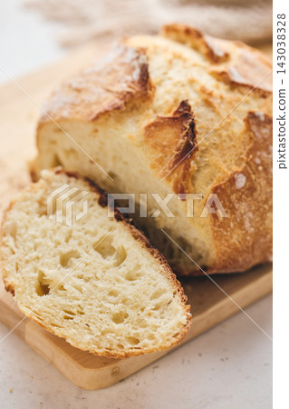 Sliced artisan sourdough bread with airy crumb on wooden board, glass of milk, and knitted cloth. Ideal for culinary, baking, and food photography projects. Sliced artisan sourdough bread with airy crumb on wooden board, glass of milk, and knitted cloth. Ideal for culinary, baking, and food photography projects. 143038328