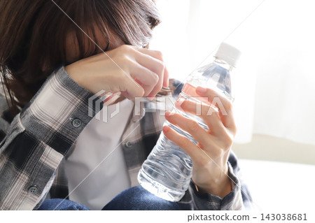 一位女士正在喝瓶裝水補充水分。 143038681