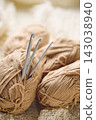 Crochet hooks and balls of beige and brown yarn on white knitted background. Knitting, crocheting supplies. 143038940
