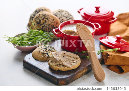 Gourmet Liver Pate Appetizer with Sesame Seed Bagels and and Fresh Pea Shoots on Rustic Wooden Board 143038943