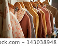Women's clothing on hangers made of natural fabrics, calm pastel colors in an eco-friendly and retro style. 143038948