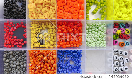 Colorful round and tubular beads arranged in separate compartments of a storage box, creating a bright palette for jewelry design, beadwork and creative handmade projects. Colorful round and tubular beads arranged in separate compartments of a storage box, creating a bright palette for jewelry design, beadwork and creative handmade projects. 143039080