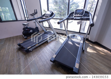 Modern Commercial Treadmills and Stationary Bike in Bright Gym Near Windows Modern Commercial Treadmills and Stationary Bike in Bright Gym Near Windows 143039153