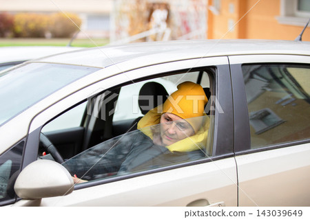 Woman sits inside a car wearing a yellow beanie while looking out of the window on a cold day Woman sits inside a car wearing a yellow beanie while looking out of the window on a cold day 143039649