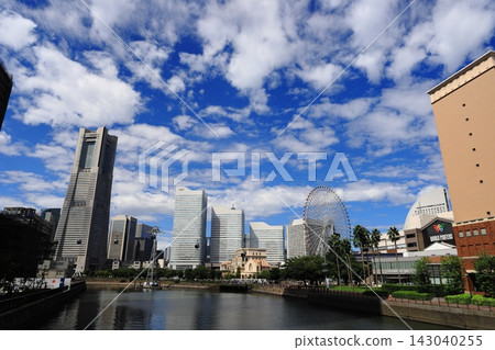 A wide-angle shot of the area around Yokohama Landmark Tower against a blue sky and clouds. A wide-angle shot of the area around Yokohama Landmark Tower against a blue sky and clouds. 143040255