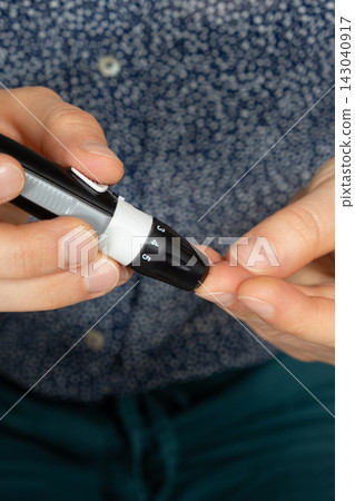 Using lancet device to prick finger for blood sugar test close up 143040917