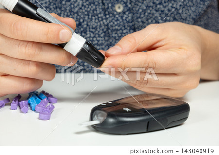 Close-up of woman pricking finger for blood glucose test at home Close-up of woman pricking finger for blood glucose test at home 143040919