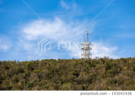在晴朗的秋日天空下,一座白色的無線電塔高聳在山頂。 在晴朗的秋日天空下,一座白色的無線電塔高聳在山頂。 143041436