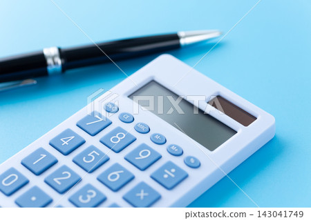 Blue calculator and ballpoint pen, blue background 143041749