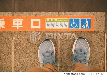 一名穿著運動鞋的人站在火車入口處,地板上標示了優先座位區域。 一名穿著運動鞋的人站在火車入口處,地板上標示了優先座位區域。 143042165