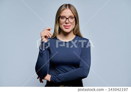 Smiling young woman in dark blue long-sleeve top on light background Smiling young woman in dark blue long-sleeve top on light background 143042197
