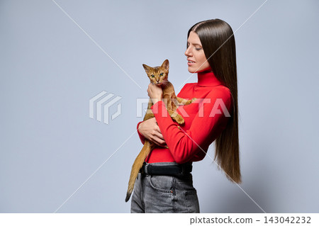 Smiling woman holding Abyssinian cat profile isolated on light gray background 143042232
