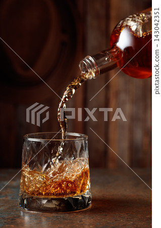 Whisky is poured into a crystal glass. Whisky is poured into a crystal glass. 143042351