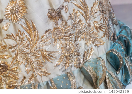 Ornate gold floral embroidery decorates vintage silk fabric Ornate gold floral embroidery decorates vintage silk fabric 143042559