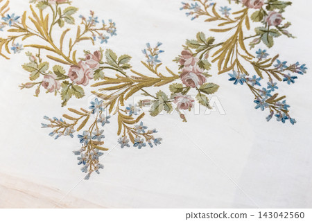 Delicate vintage floral embroidery on white linen featuring pink roses Delicate vintage floral embroidery on white linen featuring pink roses 143042560