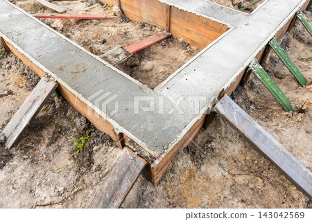 Concrete foundation footings poured into wooden formwork 143042569