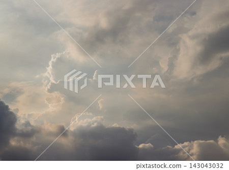 a dramatic, multi-layered cloudscape bathed in a soft, ethereal glow. The composition beautifully captures the contrast between light and shadow. 143043032