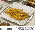 Crispy Seasoned French Fries on Checkered Paper in a Metal Tray 143043220