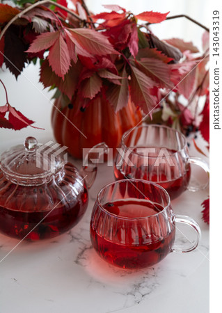 Autumn tea set with red leaves and pumpkin decor on marble surface composition Autumn tea set with red leaves and pumpkin decor on marble surface composition 143043319
